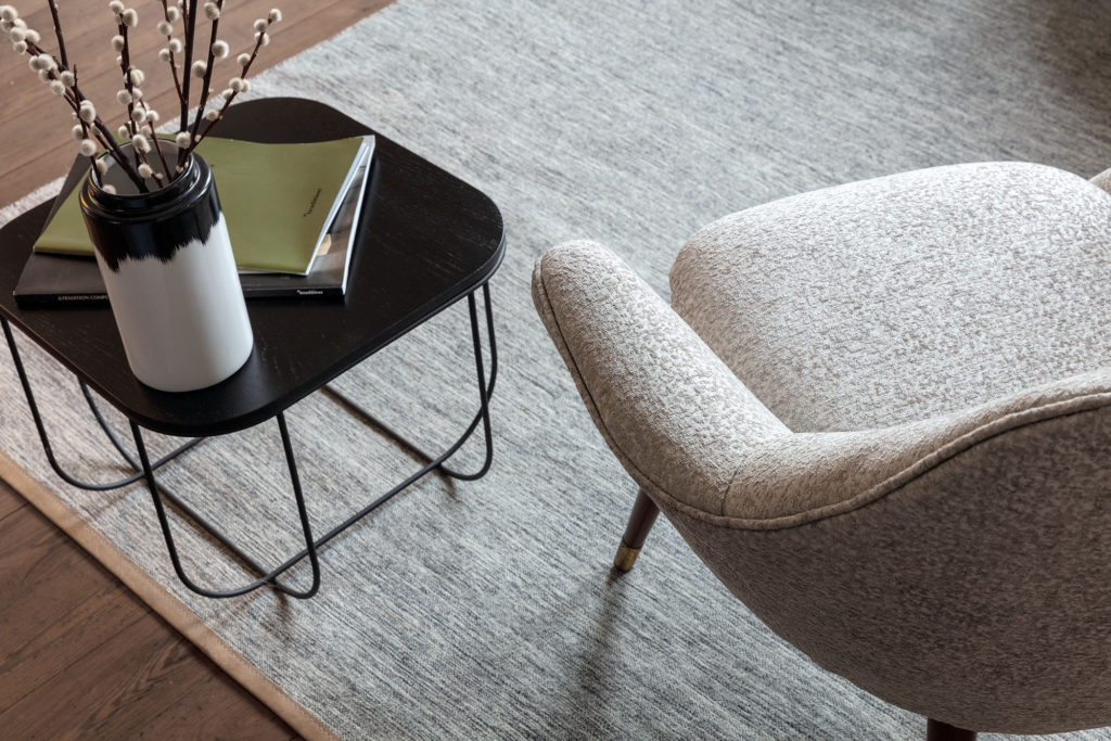 A simple chair and table arrangement on a decorative rug within a well-lit room
