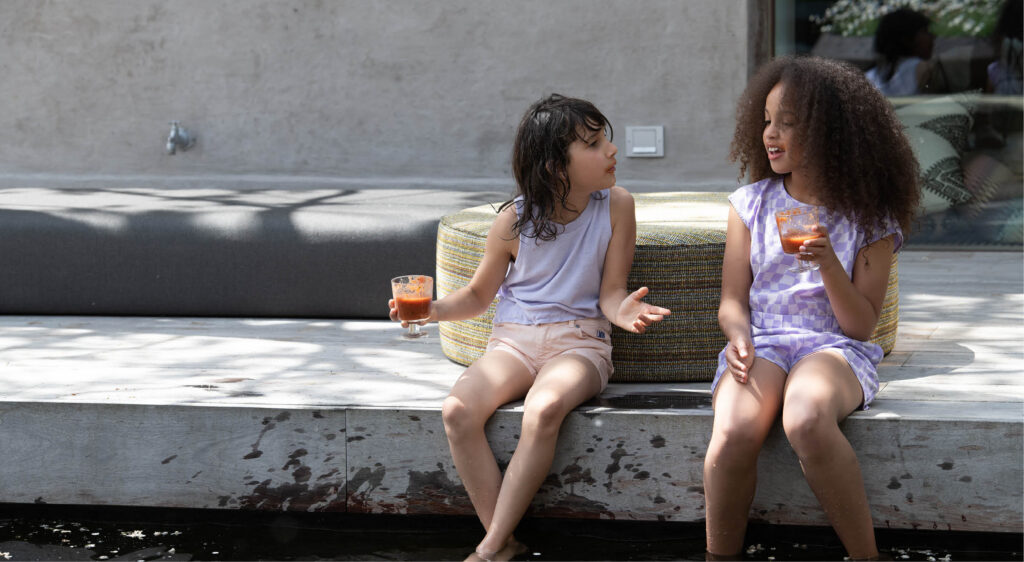 Two girls relax on a dock, sipping drinks and enjoying each other's company by the water
