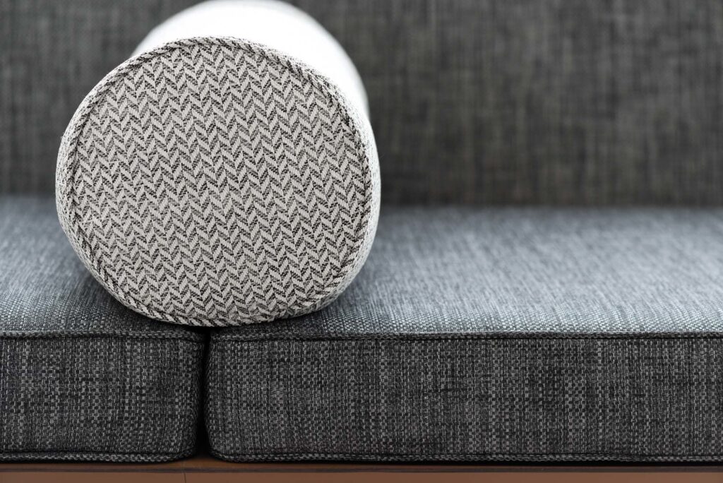 close up of the round grey armrest on a darker coloured sofa