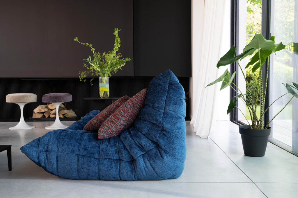 a vibrant prussian blue modern beanbag style sofa sits on the floor of a minimalist living room