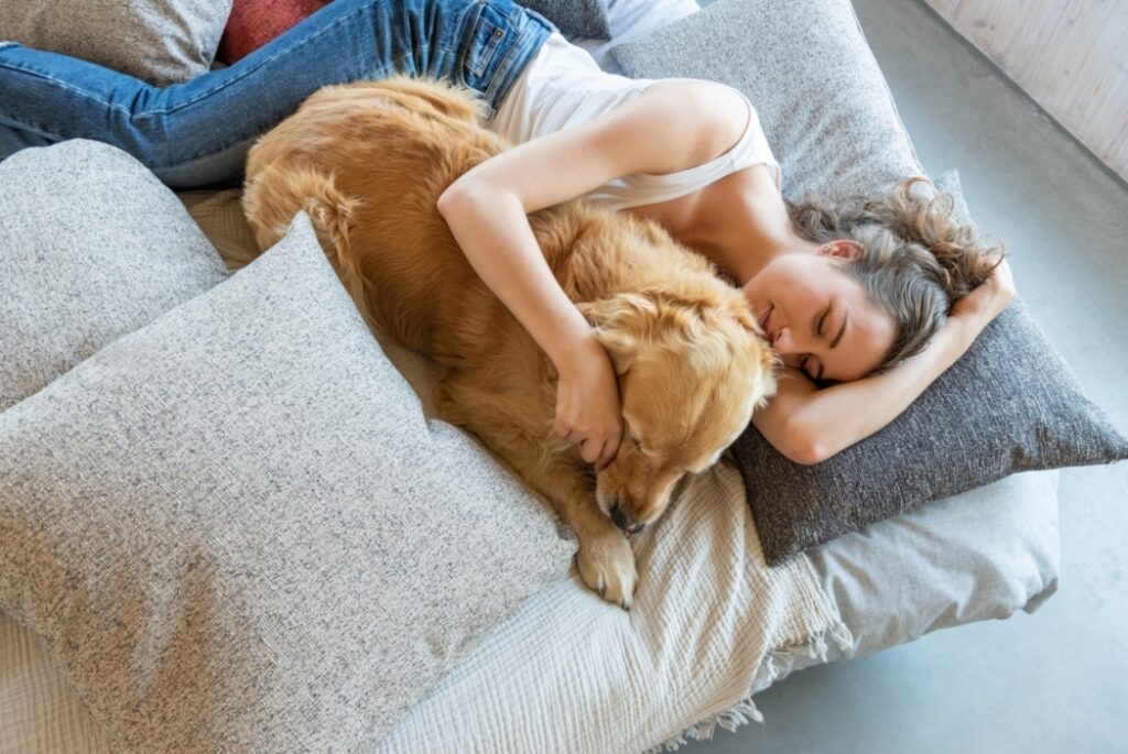 a relaxed woman cuddles her dog on neutral coloured cushions upholstered in fibreguard