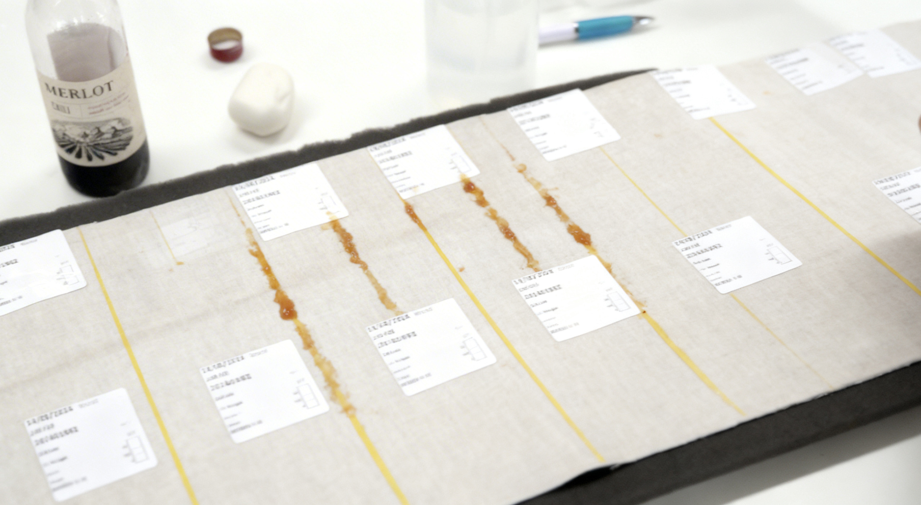 a long panel of beige coloured performance fabric with different stains applied in strips to test cleanability