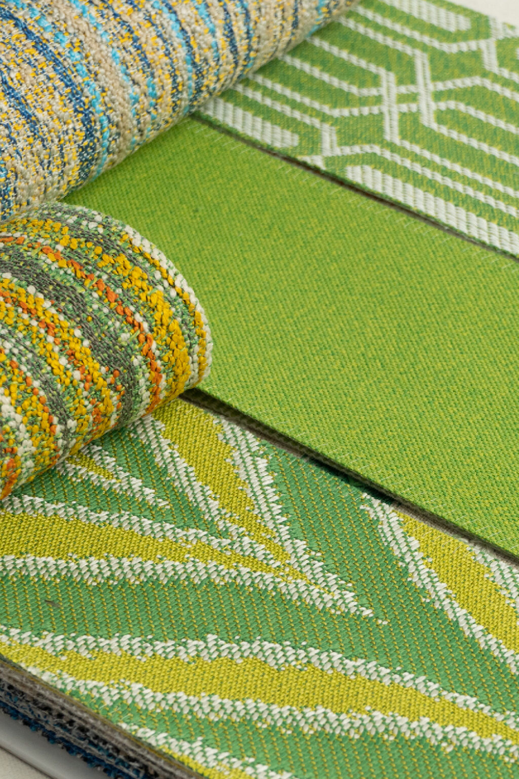 A stack of bright green fabric swatches creating a visually appealing display of colours and patterns