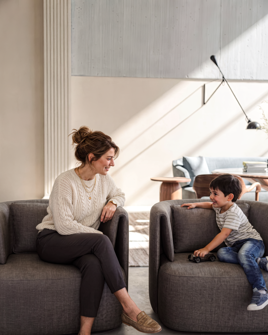 A mother and son sit in matching modern chairs in a relaxed cheerful yet elegant space